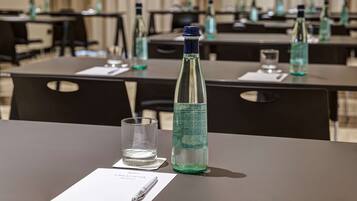 A conference room with tables, chairs, water bottles, glasses, and a pen on a notepad.