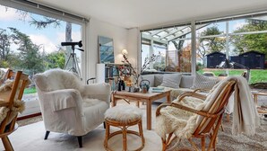 A spacious living room with a large window, a sofa, a chair, and a table with decorative items. - 3 bedroom beautiful home in Gudhjem (Gudhjem)