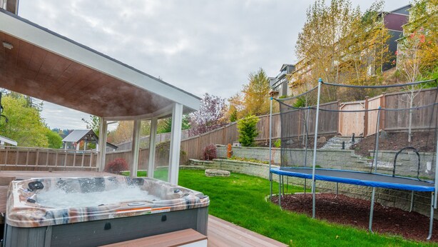 A hot tub with steps, a trampoline, and a covered patio area. - Bonney Lake House INN  W/Jacuzzi and Centralized AC (Bonney Lake)