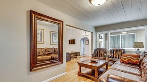 A living room with a large mirror, leather sofas, wooden coffee table, and a chandelier. - Family-Friendly Home 2 Mi to Dtwn Colorado Springs (Colorado Springs)