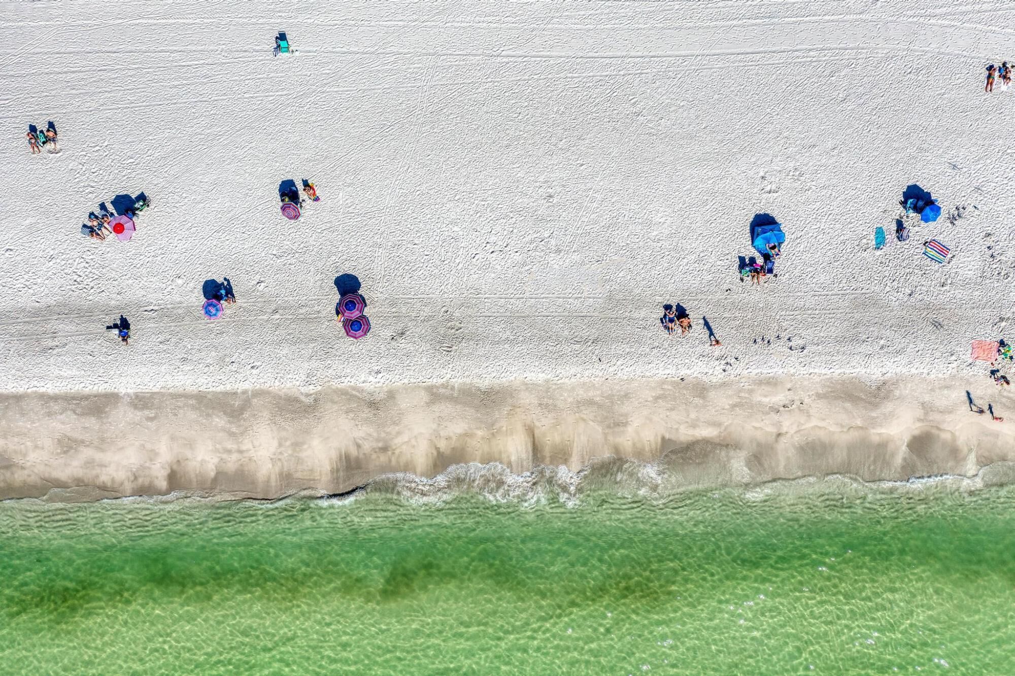 A beach with people and beach chairs.