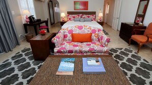 A hotel room with a bed, a sofa, a desk, and two books on the floor. - Shared Pools & Private Beaches! Room w/Garden View (Sandys Parish)
