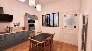 Enjoy meals at the dining table in this kitchen, equipped with a stove, oven, and refrigerator.