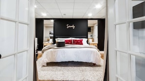 Une chambre moderne avec un grand lit, une tête de lit noire et une enseigne « Sérénité » au-dessus du lit.