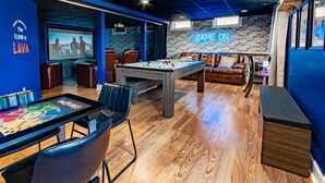 Un espace intérieur accueillant, doté d’une table de billard, de fauteuils en cuir et d’un néon lumineux sur lequel on peut lire : « C’est parti pour le jeu ! ».