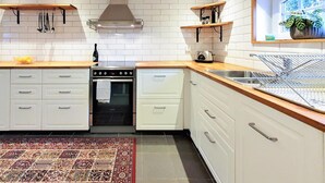 Een keuken met witte kastjes, een roestvrijstalen oven en een raam met een plant.