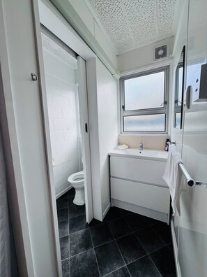 Un baño pequeño con inodoro blanco, lavamanos y ventana.