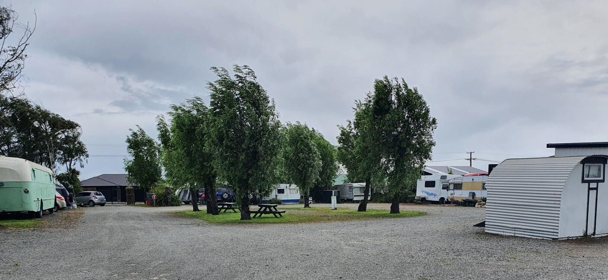 Een camping met campers, een picknicktafel en een klein gebouwtje.