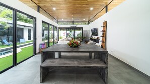 Une cuisine moderne avec un plafond en bois, de grandes fenêtres et un îlot central agrémenté d’un arrangement floral.