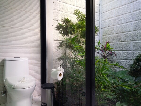 A bathroom with a toilet, a trash bin, and a toilet paper holder.