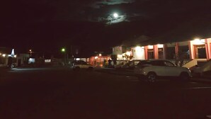 A nighttime street scene with buildings and parked cars. - Hostería Cotopaxi Tour (Tanicuchi)