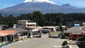 A parking lot with a view of a snow-capped mountain in the background. - Hostería Cotopaxi Tour (Tanicuchi)
