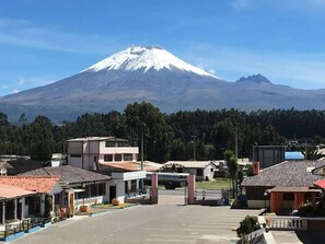 A parking lot with a view of a snow-capped mountain in the background. - Hostería Cotopaxi Tour (Tanicuchi)