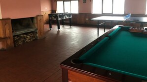 A billiards room with a pool table, a foosball table, and a fireplace. - Hostería Cotopaxi Tour (Tanicuchi)