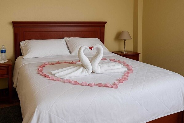 A neatly made bed with a swan and heart-shaped decoration made of rose petals. - Hostería Cotopaxi Tour (Tanicuchi)