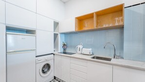 A compact kitchen with a washing machine, a toaster, and a sink. - GuestReady - Cozy Bright apartment with a Balcony (Porto)