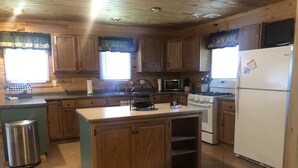 A kitchen with wooden cabinets, a stove, a microwave, and a refrigerator. - Powerhouse Cabin Black River falls Wisconsin  (Black River Falls)