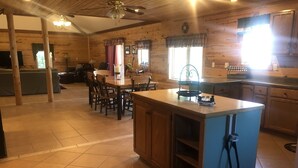 A spacious kitchen with a central island, wooden cabinets, and a dining area with chairs. - Powerhouse Cabin Black River falls Wisconsin  (Black River Falls)