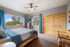 A bedroom with a bed, a ceiling fan, a wardrobe, and large windows. - Family-Friendly Jefferson Cabin w/ Amazing Views! (Jefferson)