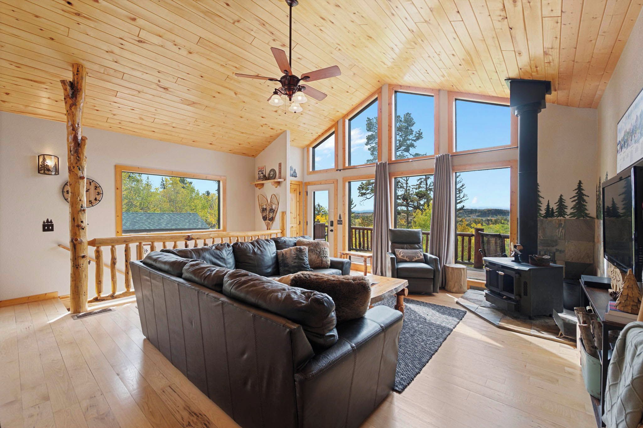 A spacious living room with a large sofa, a fireplace, and a view of the outdoors through large windows.