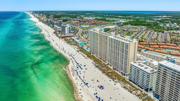 A coastal cityscape with a beach, high-rise hotels, and a clear blue sky.
