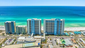 A beachfront hotel with multiple high-rise buildings, a sandy beach, and a clear blue ocean.