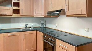 A kitchen with wooden cabinets, a stainless steel sink, a coffee maker, and a stove.