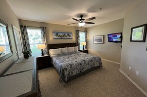 A bedroom with a bed, a ceiling fan, a TV, and artwork on the walls. - 2-102 Legacy Dunes, Lake Views, Heated Pool, Free Wifi and Parking (Kissimmee)