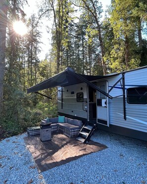 A recreational vehicle with an attached awning, a fire pit, and outdoor seating. - Quiet, majestic views of the Shire in a cozy glamping set up!  (Brush Prairie)