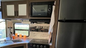A compact kitchen with a microwave, stove, oven, and refrigerator. - Quiet, majestic views of the Shire in a cozy glamping set up!  (Brush Prairie)