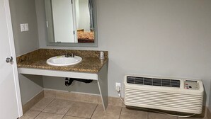 A bathroom with a sink, mirror, and air conditioning unit. - Stay Inn Motel (Harbor City)
