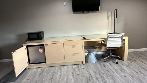 A compact office space with a desk, a microwave, a small refrigerator, and a chair. - Stay Inn Motel (Harbor City)