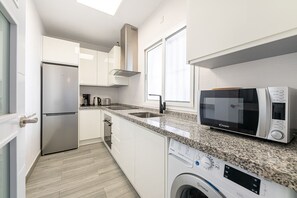 A modern kitchen with a built-in dishwasher, a microwave, and a stainless steel refrigerator.