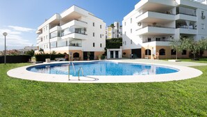 En moderne lejlighedskompelks med swimmingpool omgivet af velholdt græsplæne.
