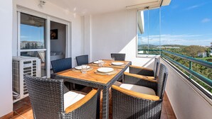 En balkon med et spisebord, fletstole og udsigt over landskabet.
