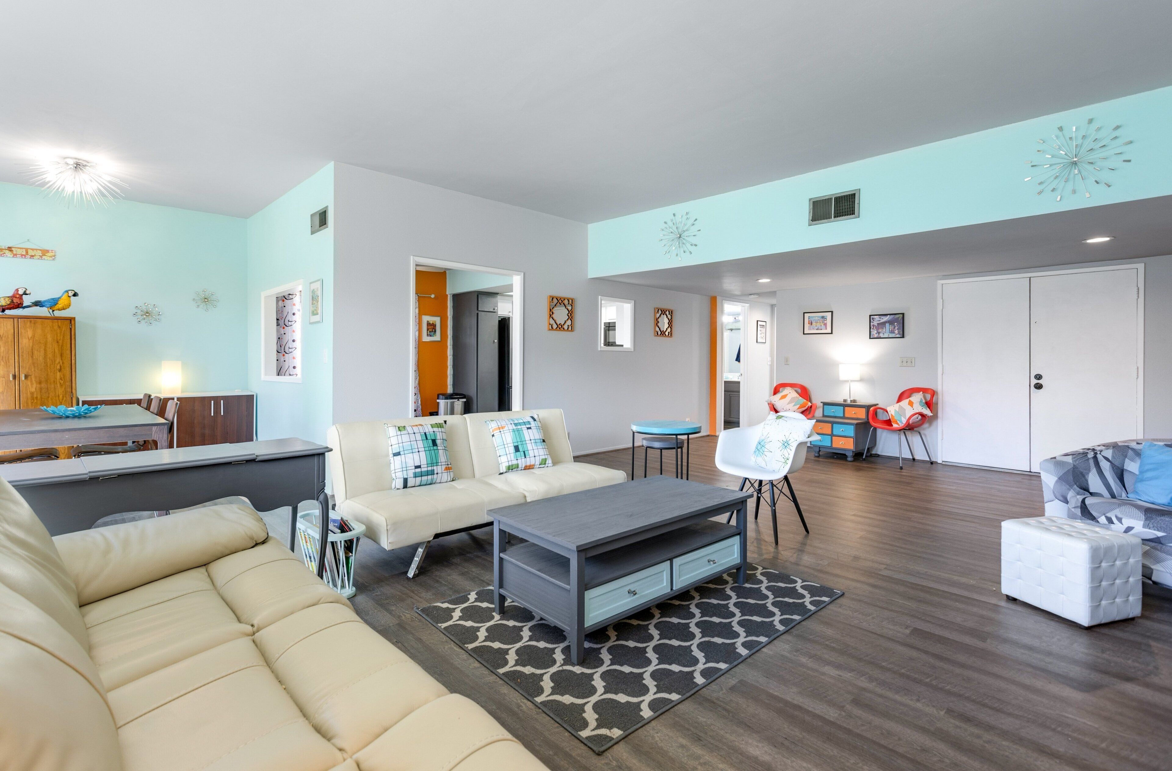 A modern living room with a sofa, coffee table, and a dining area with a table and chairs.