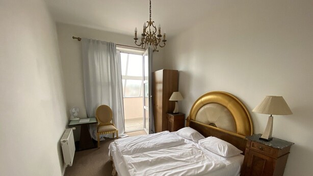 Una camera d'albergo con un letto, una scrivania, una sedia, un armadio e un lampadario.