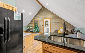Cozy kitchen with a modern refrigerator, stainless steel sink, and wooden countertop.