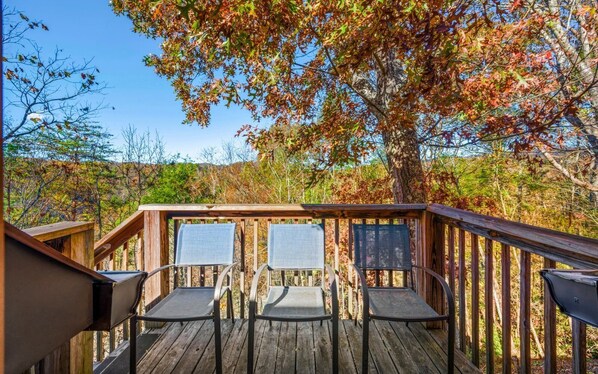 Enjoy outdoor dining or relaxation on this deck surrounded by trees with beautiful foliage.