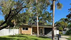 Une maison de plain-pied avec une façade en pierre, un garage et une pelouse bien entretenue.