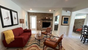 Un salon avec un canapé rouge, des fauteuils en cuir marron, un tapis à motifs et une cheminée en pierre.