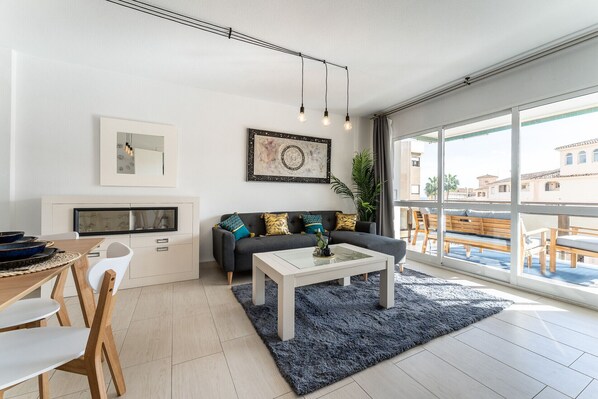 A modern living room with a sofa, coffee table, and dining area.