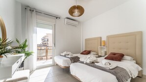 Ein modernes Schlafzimmer mit zwei Betten, einem weißen Schreibtisch und einem großen Fenster.