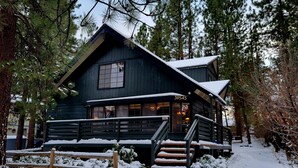 En mörk trästuga med en överbyggd veranda och en skylt med nummer 39545.