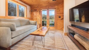 Un salon chaleureux avec un plafond en bois, un canapé, une table basse et un téléviseur à écran plat.