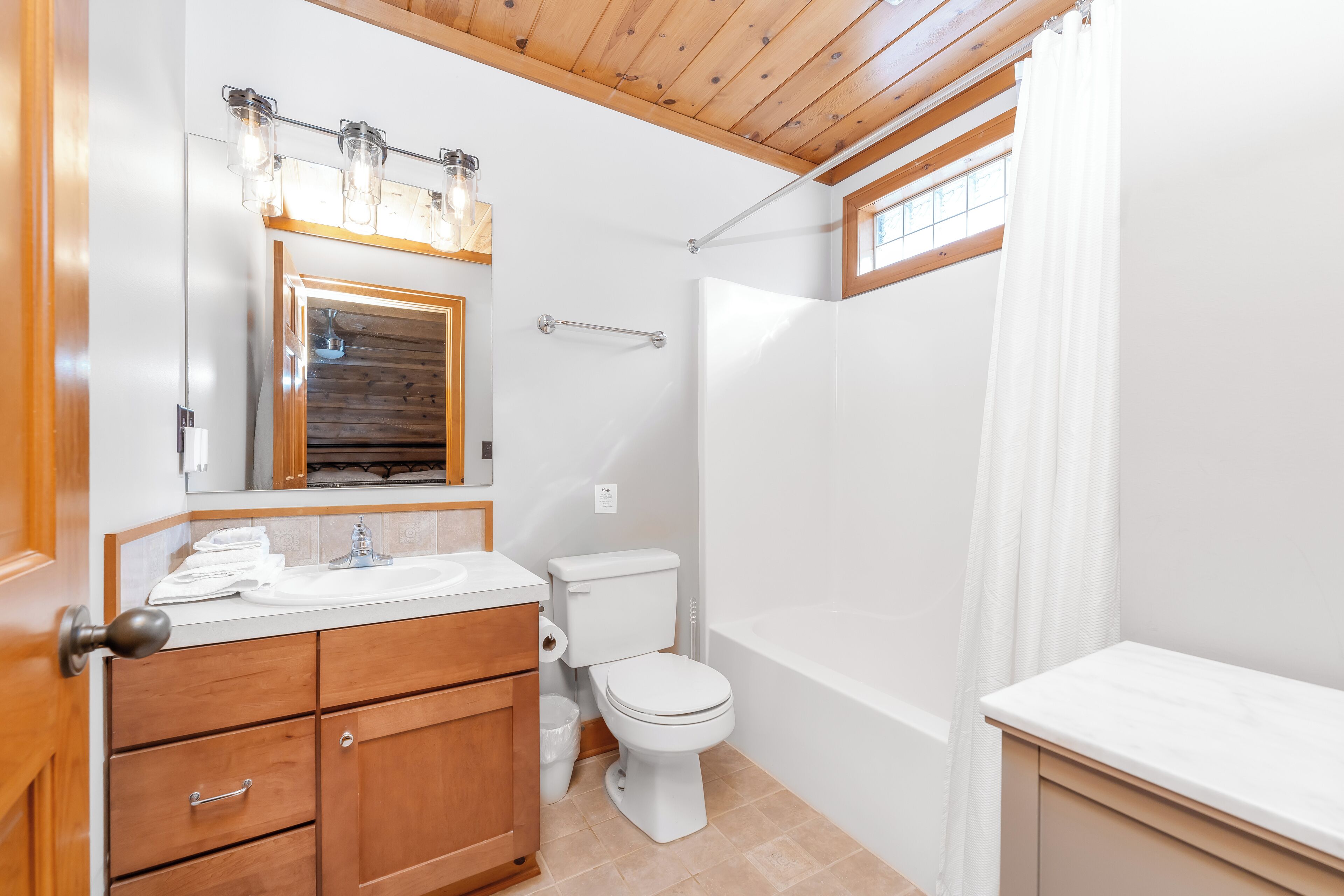 Une salle de bain avec un meuble-lavabo en bois, un lavabo blanc, des toilettes et une baignoire.