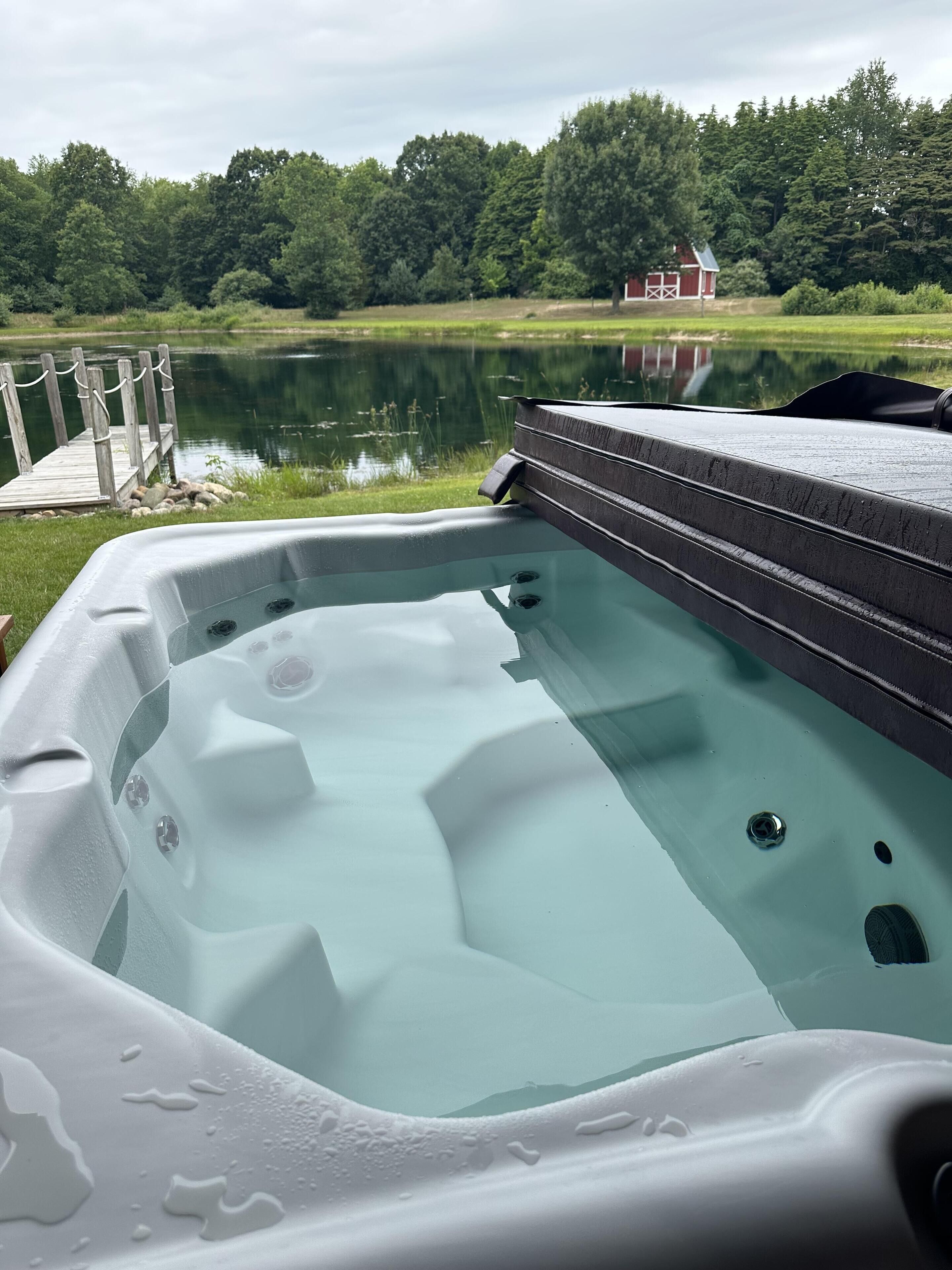 A hot tub with a wooden deck and a lake view.