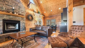 Un intérieur de chalet chaleureux avec une cheminée, un canapé en cuir et un coin repas.