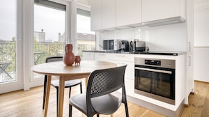 A modern kitchen with white cabinets, a round dining table, and a black chair.