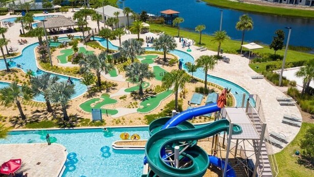 A resort pool area with a water slide, multiple swimming pools, and a golf course. - 5BR/5BA Game/Pool Villa 9 Miles to Disney (Kissimmee)